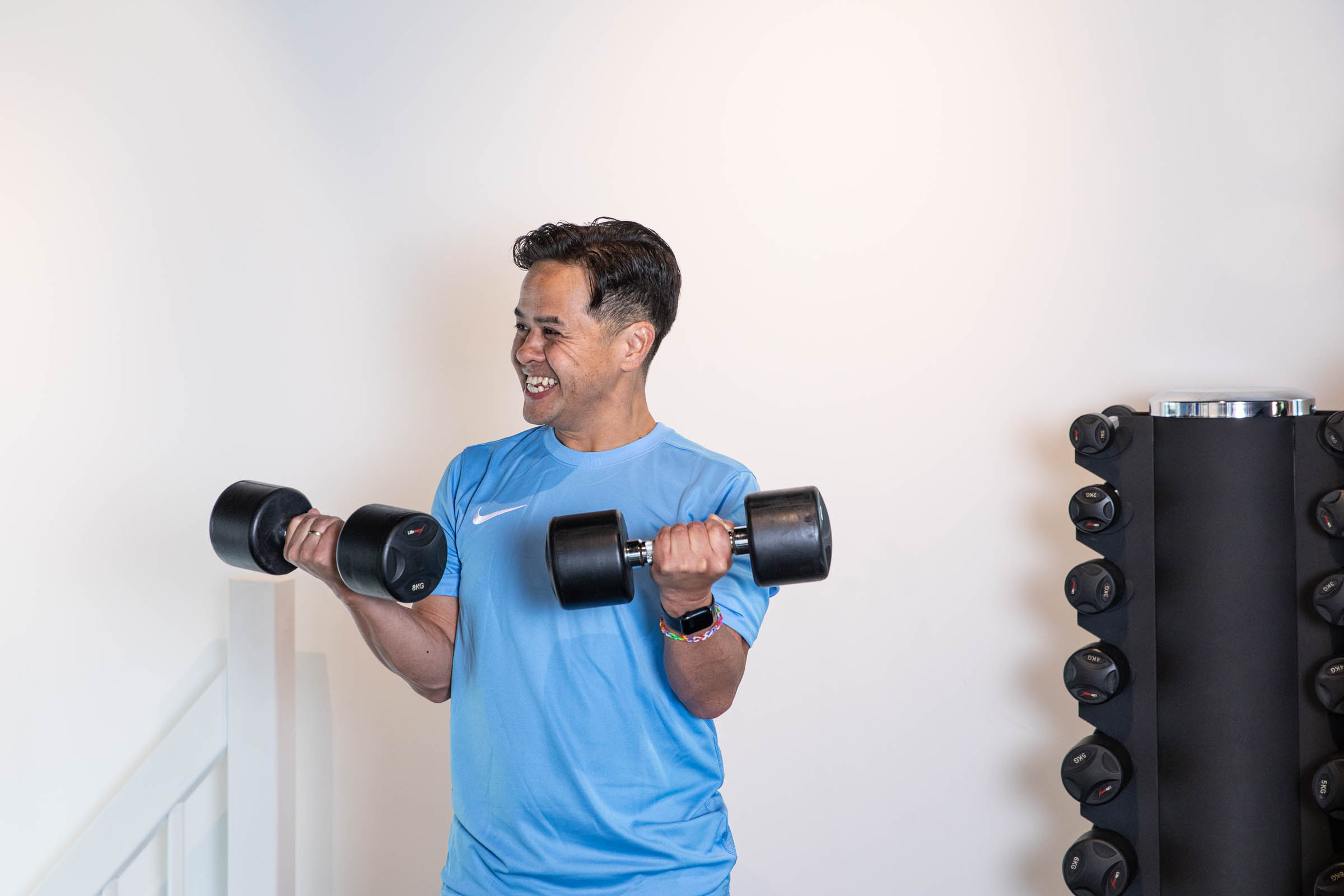 Man die vrolijk aan het trainen is met dumbbells in zijn handen
